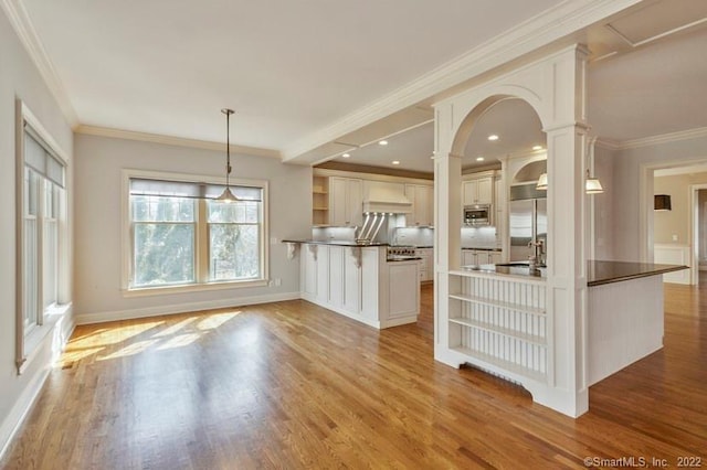 kitchen with decorative columns, a peninsula, open shelves, and wood finished floors