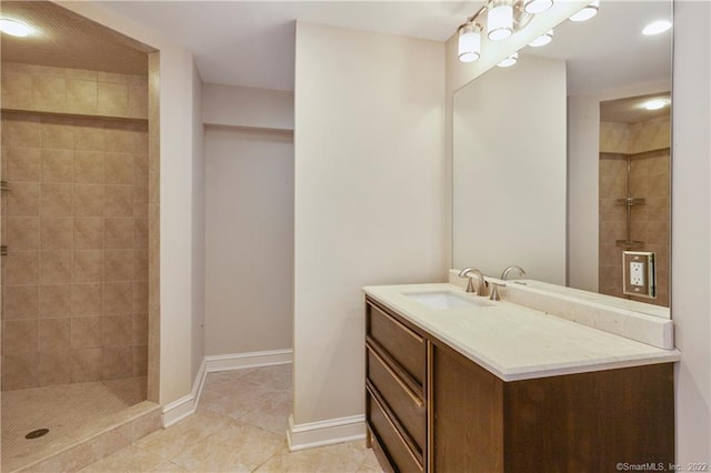 bathroom featuring tile patterned floors, tiled shower, vanity, and baseboards