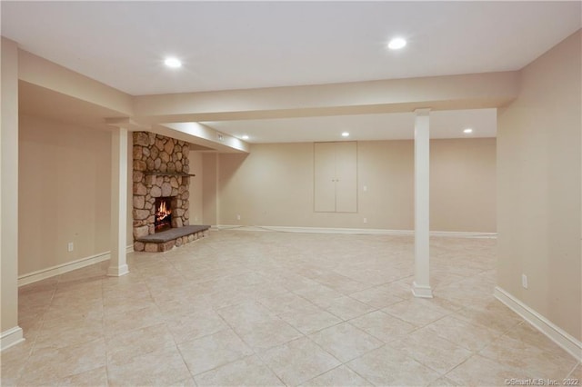 finished below grade area featuring light tile patterned floors, a fireplace, baseboards, and recessed lighting
