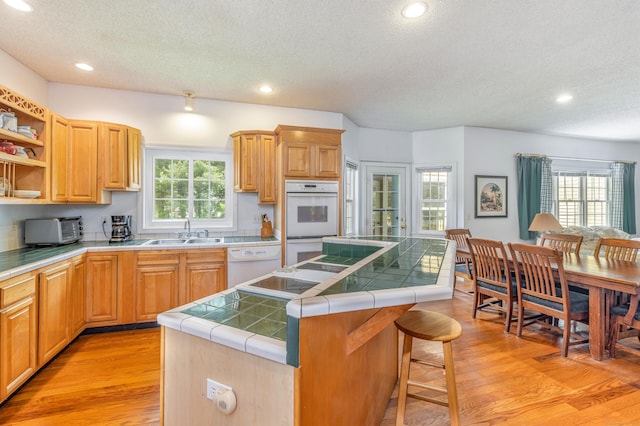 14 Fieldstone Dr, Mansfield, CT 06268 - kitchen with a textured ceiling, tile counters, a center island, white appliances, and light wood-type flooring