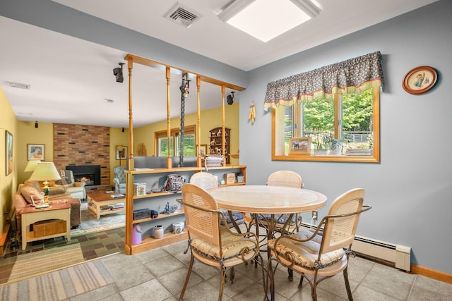 dining space featuring visible vents, baseboards, a baseboard radiator, and a fireplace
