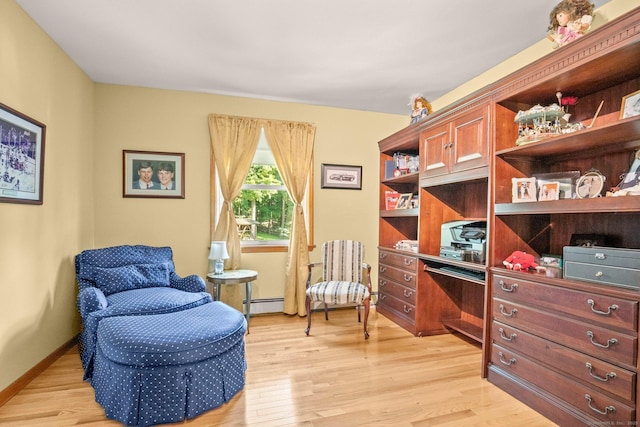 sitting room featuring light wood-type flooring, a baseboard heating unit, and baseboards