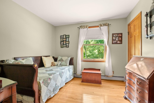 bedroom with light wood-style flooring, a baseboard radiator, and a baseboard heating unit