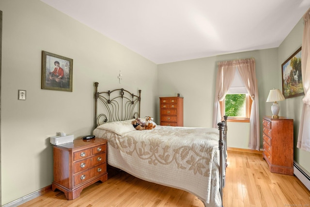 bedroom featuring baseboard heating, light wood-type flooring, and baseboards