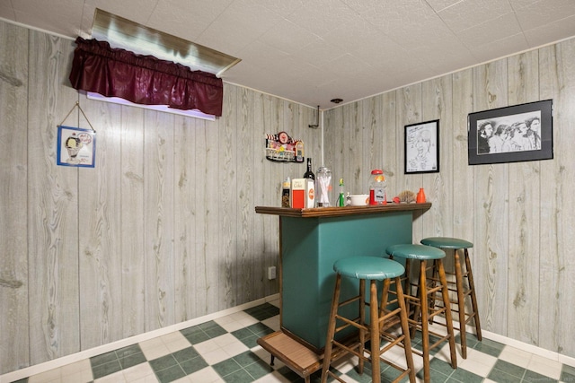 bar featuring tile patterned floors, wooden walls, and a dry bar