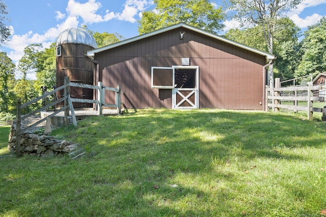 view of barn featuring fence and a lawn