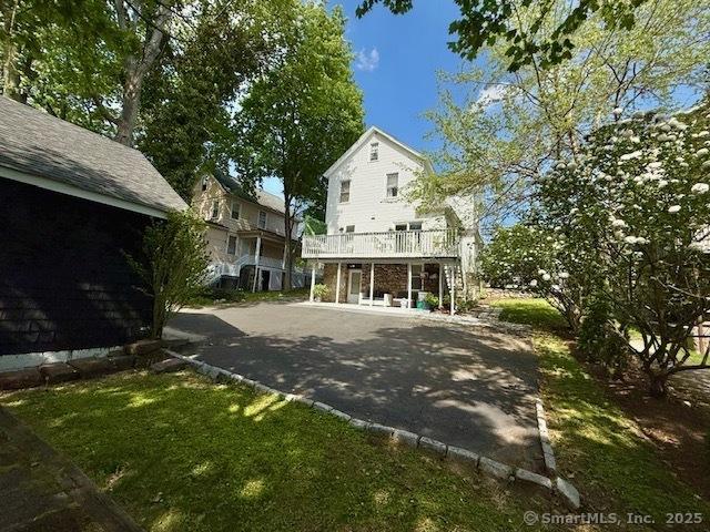 rear view of house with a wooden deck and driveway