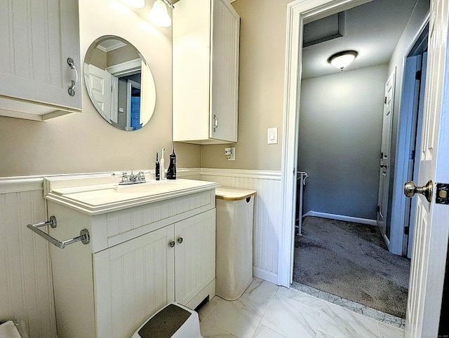 bathroom featuring marble finish floor, vanity, and a wainscoted wall