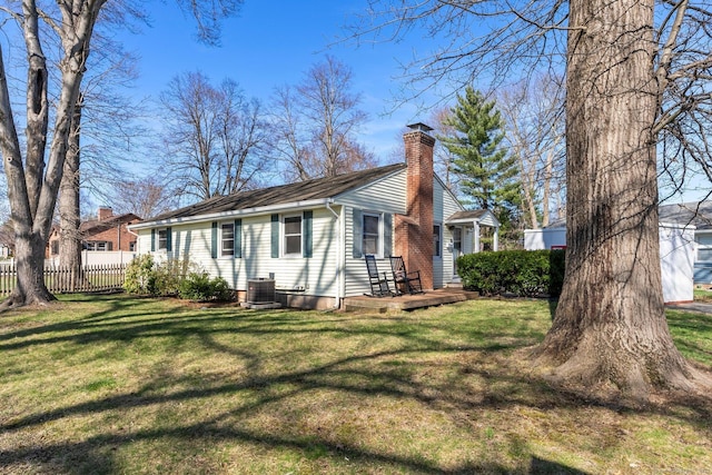 rear view of property featuring a chimney, fence, and a lawn