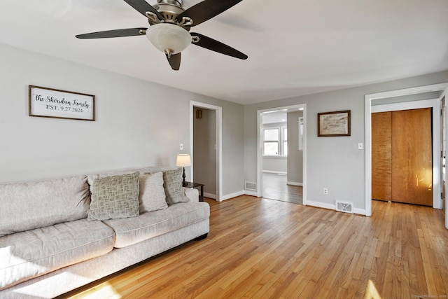 living room featuring visible vents, light wood-style flooring, and baseboards