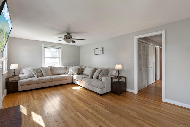 living area with light wood-type flooring, baseboards, and a ceiling fan