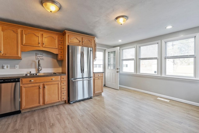 kitchen with stainless steel appliances, visible vents, brown cabinets, and a sink