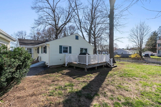 back of house featuring a yard, a wooden deck, and fence