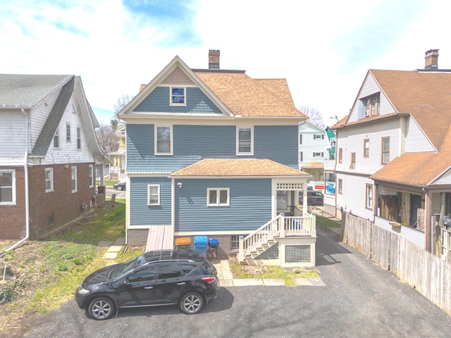 back of property with a chimney and a shingled roof