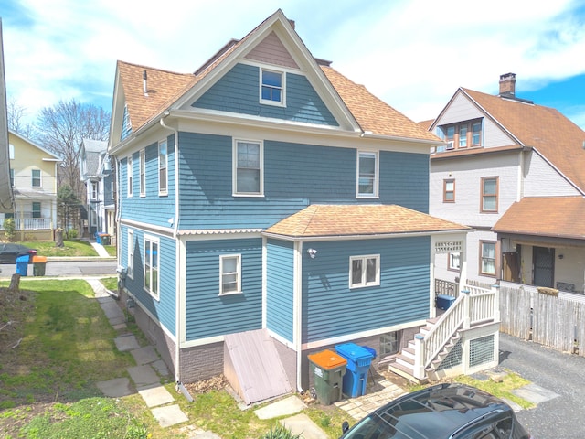 rear view of property featuring a shingled roof