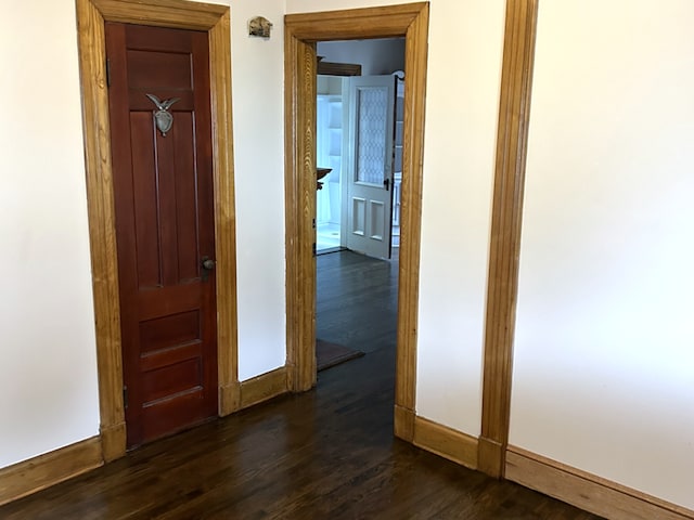 hall with dark wood-style flooring and baseboards