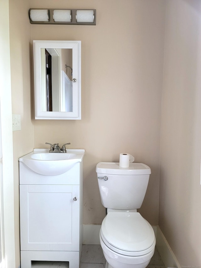 half bathroom featuring vanity, baseboards, and toilet