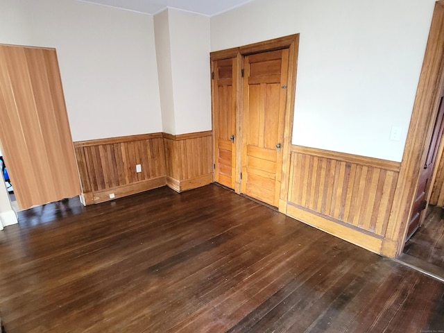 spare room featuring wood walls, hardwood / wood-style flooring, and a wainscoted wall