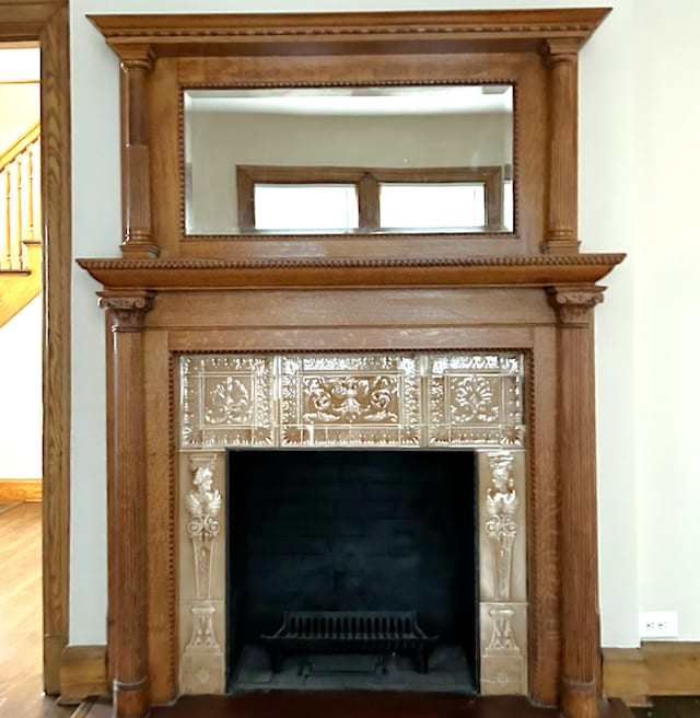 interior details with a tiled fireplace and wood finished floors