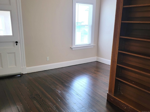 unfurnished bedroom with baseboards and dark wood-style floors