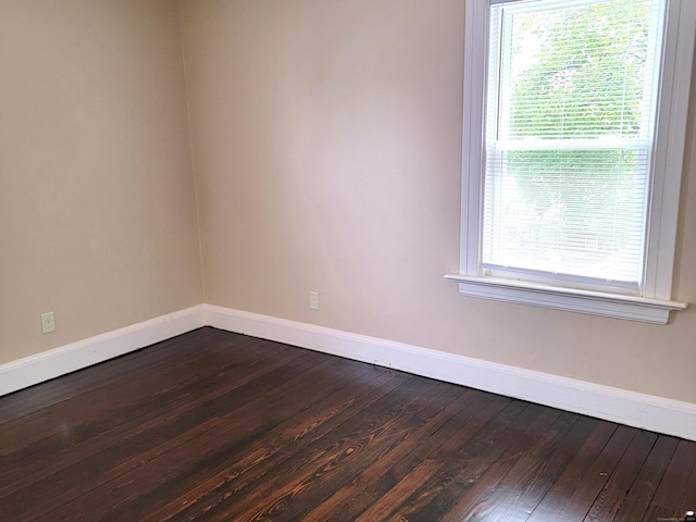 empty room featuring dark wood-style flooring and baseboards
