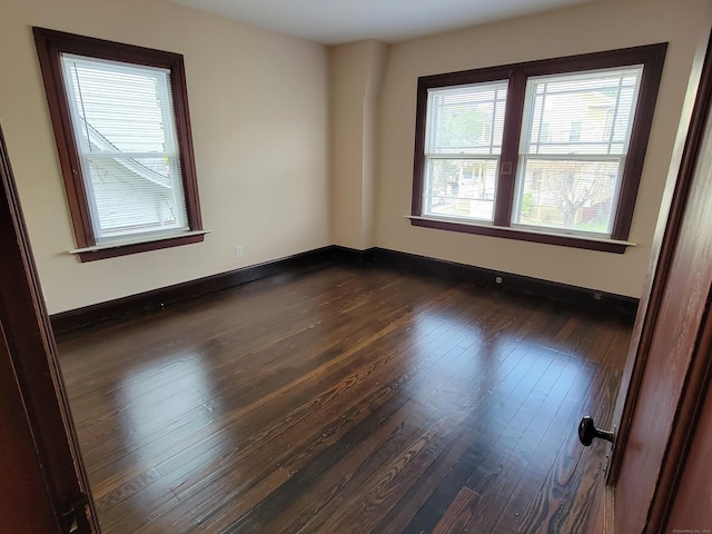 spare room featuring baseboards and dark wood finished floors