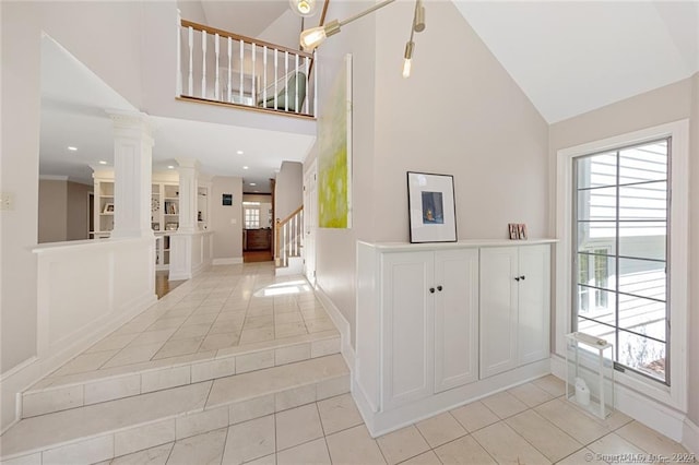 foyer featuring stairs, baseboards, high vaulted ceiling, ornate columns, and light tile patterned floors