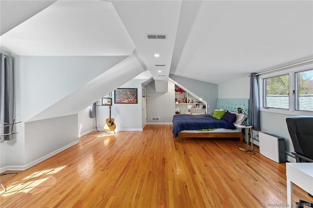bedroom with baseboards, visible vents, light wood-style flooring, and vaulted ceiling