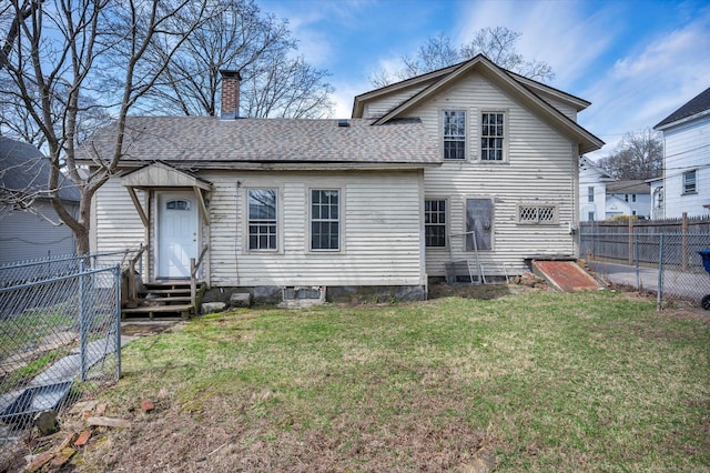 back of house with a yard, a fenced backyard, entry steps, roof with shingles, and a chimney