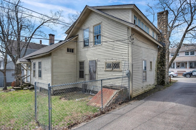 view of property exterior with a chimney, fence, and a yard