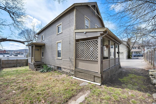 view of side of home with fence and a lawn
