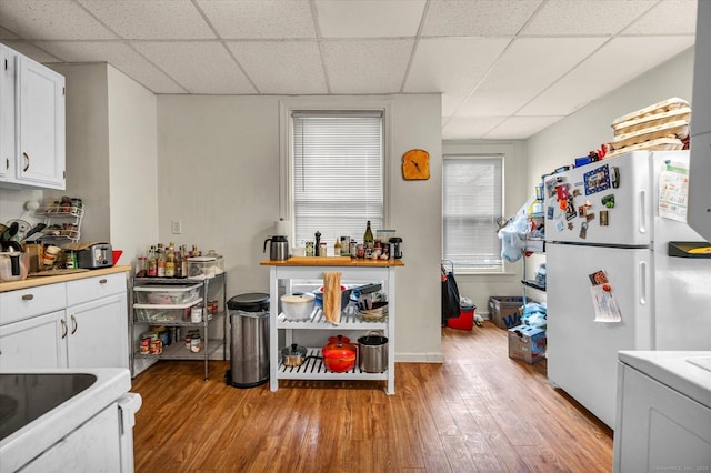 kitchen with freestanding refrigerator, a drop ceiling, and light wood finished floors