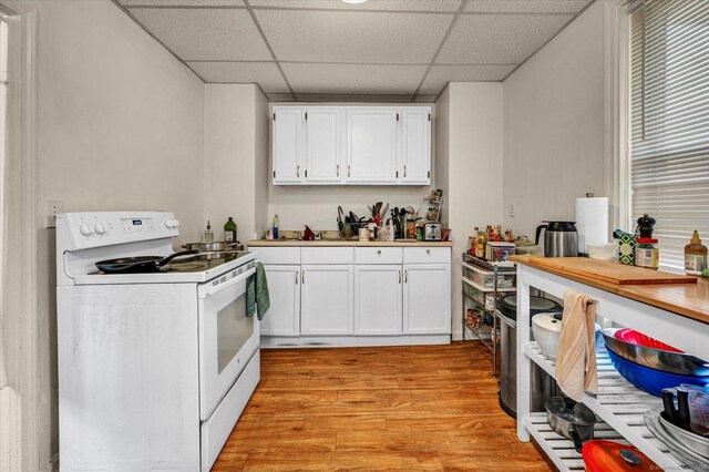 kitchen with a paneled ceiling, light wood-type flooring, light countertops, white cabinets, and white electric range