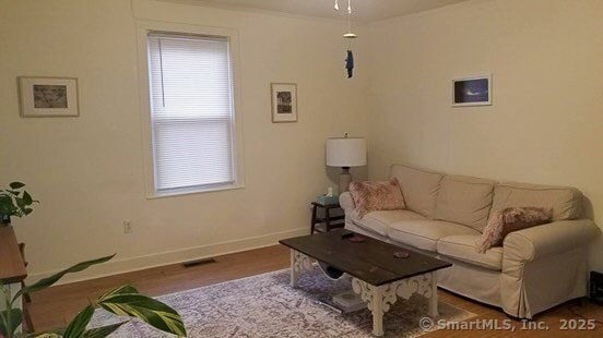 living room featuring visible vents, baseboards, and wood finished floors