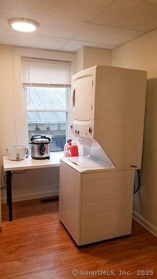 laundry area featuring stacked washer / drying machine and light wood finished floors