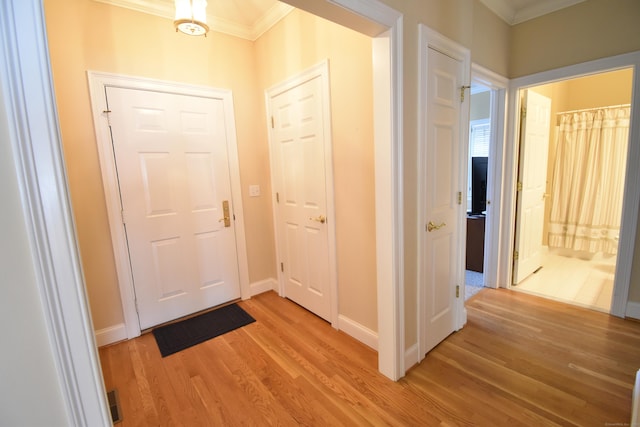 interior space featuring light wood-style floors, baseboards, crown molding, and visible vents