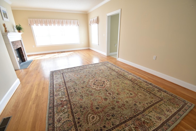 unfurnished living room featuring visible vents, baseboards, ornamental molding, wood finished floors, and a tile fireplace