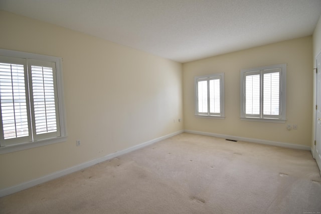unfurnished room featuring visible vents, baseboards, and light carpet