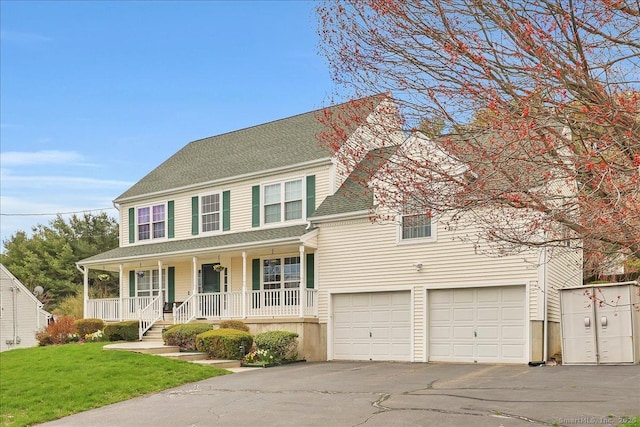 colonial inspired home with a front yard, a shingled roof, an attached garage, covered porch, and driveway