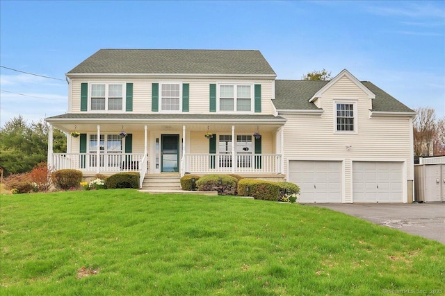 colonial house with roof with shingles, a front lawn, an attached garage, aphalt driveway, and a porch