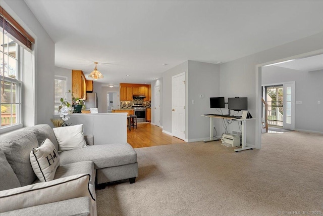 living room featuring baseboards, light carpet, and a healthy amount of sunlight
