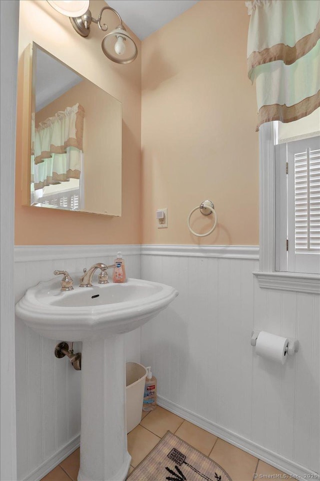 bathroom with a sink, tile patterned floors, and a wainscoted wall