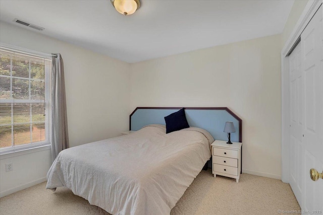 carpeted bedroom with visible vents, baseboards, and a closet