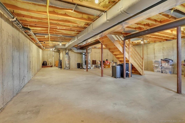 unfinished below grade area featuring stairs, heating unit, and gas water heater