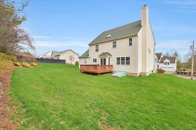 rear view of property featuring a yard, a deck, and a chimney