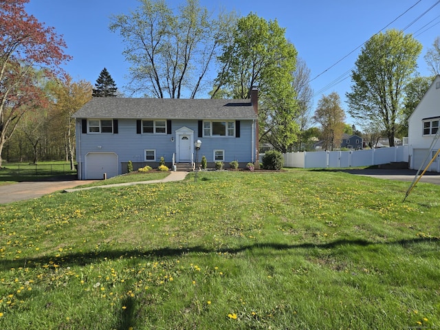 bi-level home with fence, a front lawn, a garage, a chimney, and concrete driveway