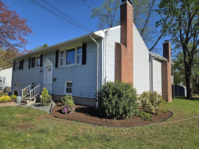 view of side of property with a yard and a chimney
