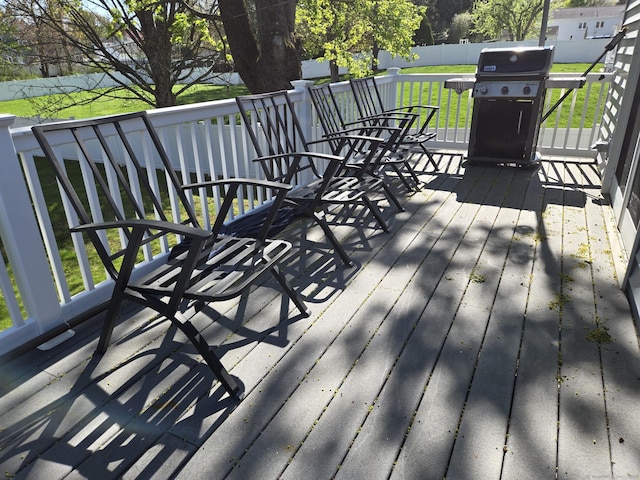 wooden terrace with a lawn, fence, and a grill