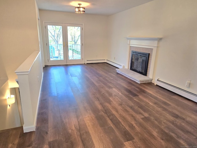 unfurnished living room with baseboard heating, dark wood-style flooring, a tiled fireplace, and french doors