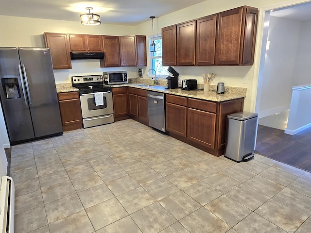 kitchen featuring light stone countertops, appliances with stainless steel finishes, a sink, a baseboard radiator, and under cabinet range hood